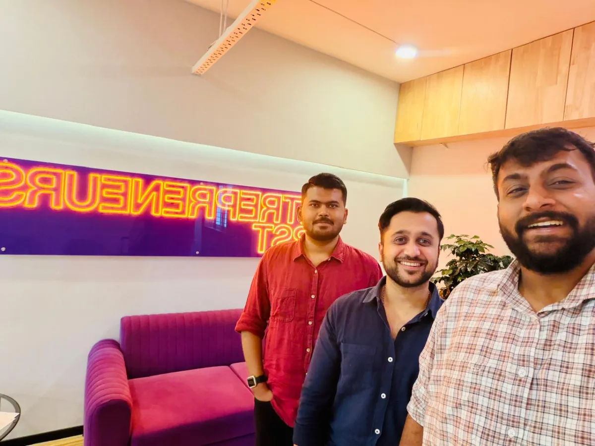 The three founders taking a selfie in front of the Entrepreneur First neon sign
