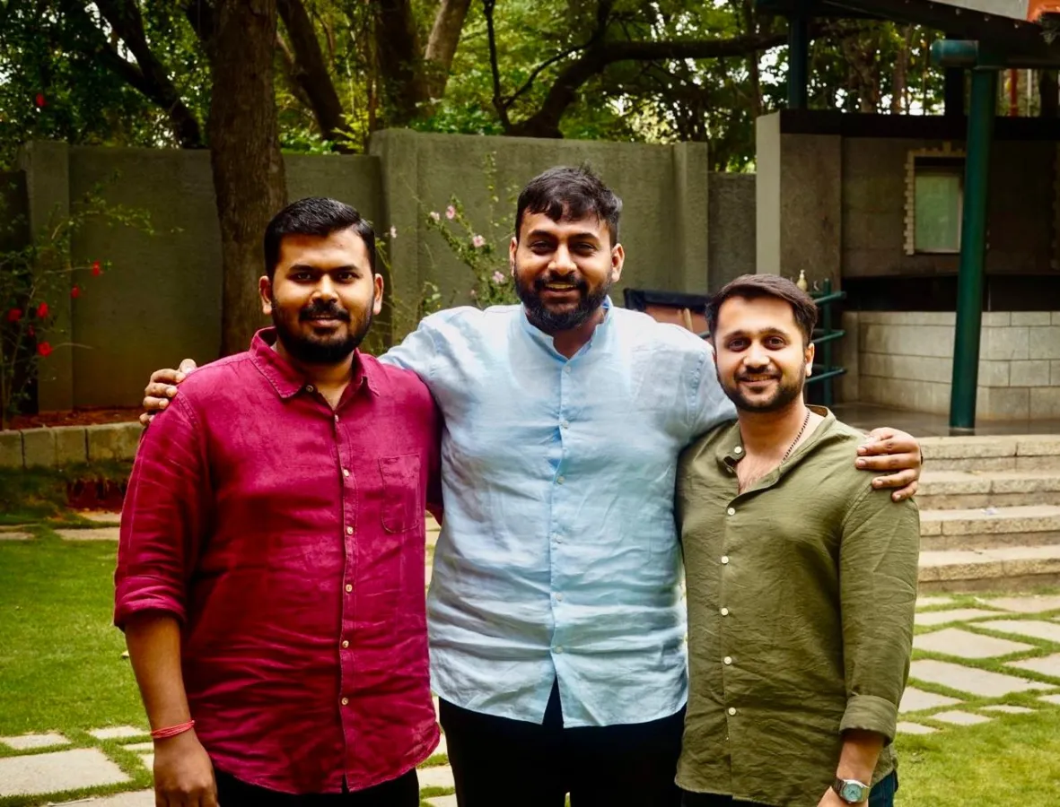 The three founders standing arm in arm in a garden
